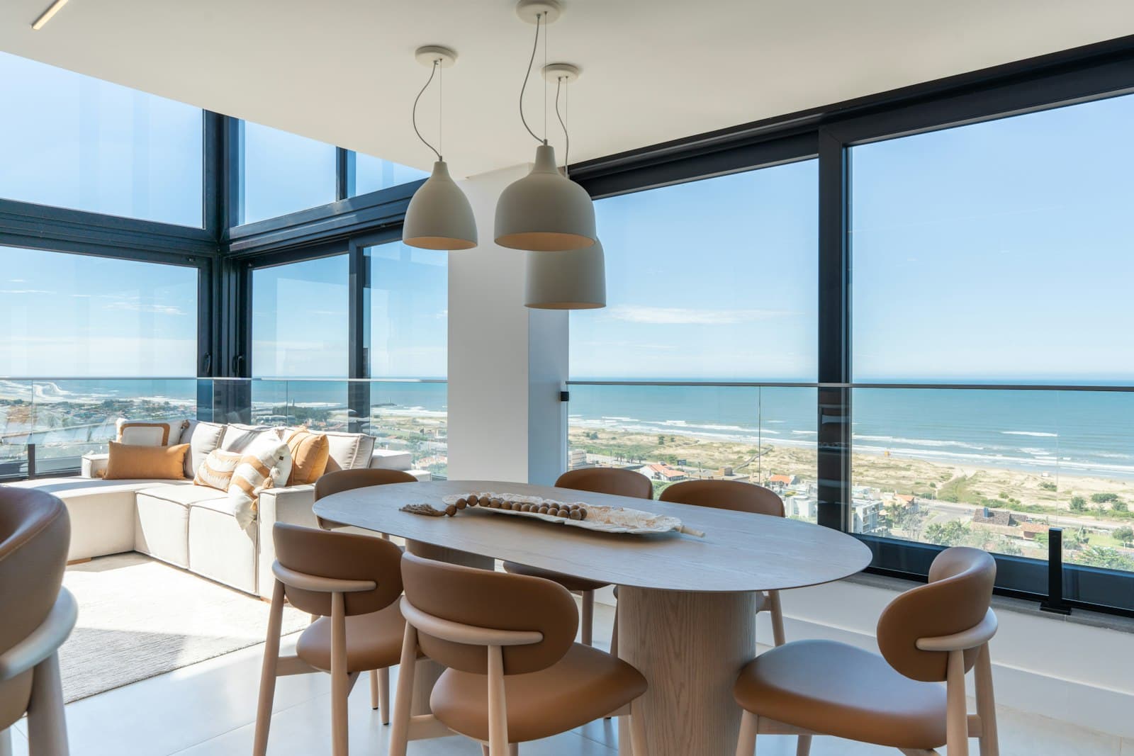 Lichte woonkamer met grote ramen en zicht op het strand